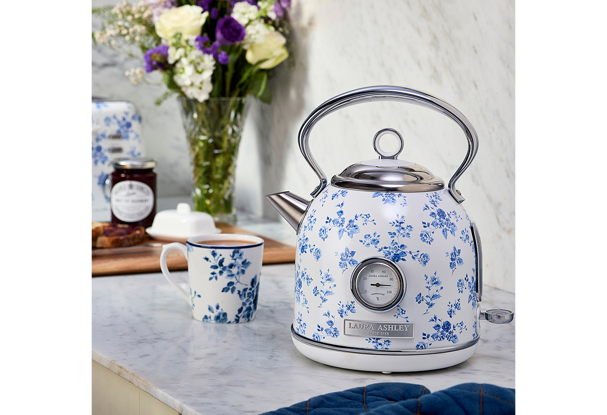 Απεικονίζονται σε ένα τραπέζι ο βραστήρας μαζί με μία κούπα καφέ.